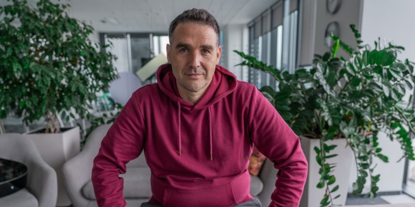 David Pokleka wearing a wearing hoodie and sitting between two plants
